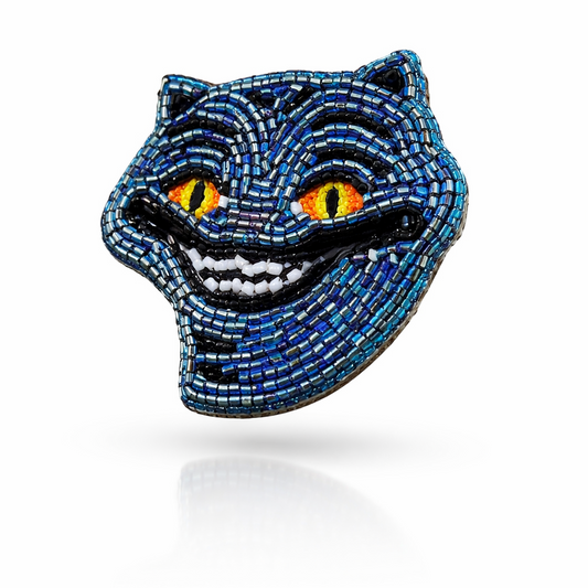 Handmade blue beaded Derpy Tiger brooch with yellow eyes and grinning smile on white background