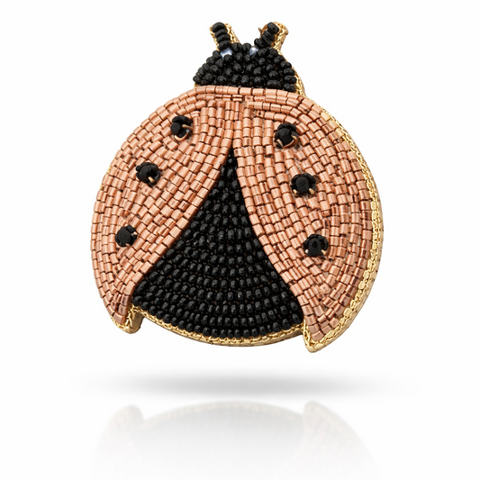Close-up of handcrafted ladybug hair clip with intricate orange and black beaded design on white background