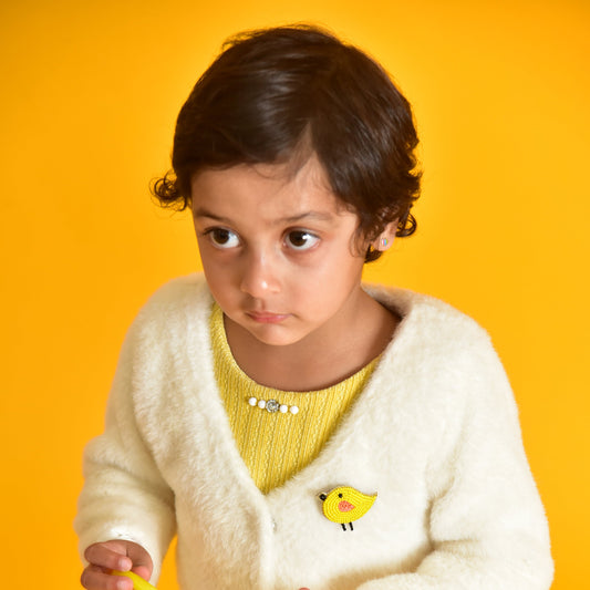 Child wearing a yellow handcrafted bird brooch on white sweater against orange background - Little Pink Llama
