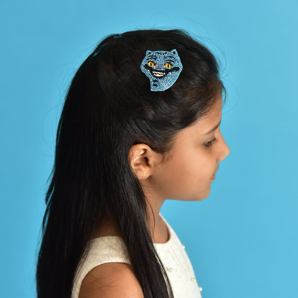 Side profile of girl with Derpy Tiger hair clip holding long dark hair against blue background