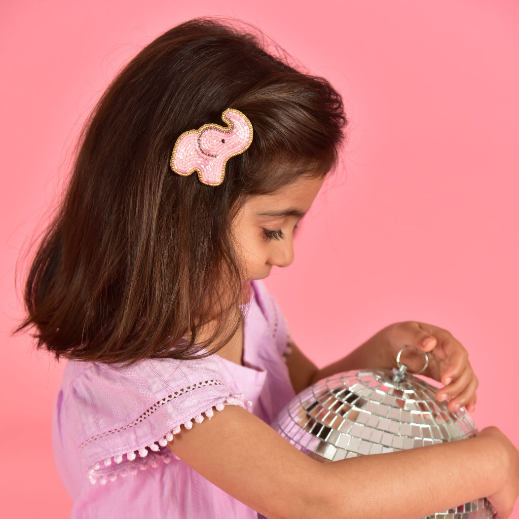 Young girl in pink dress wearing pink beaded elephant hair clip - handmade kids accessory lifestyle photo