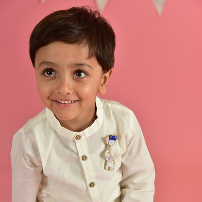 Boy smiling in white kurta wearing handmade elephant with balloons brooch – Little Pink Llama kids lapel pin on pink background