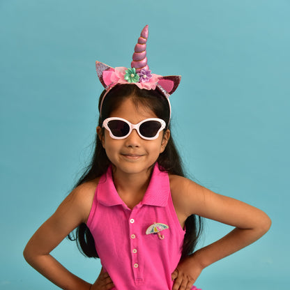 Young girl wearing a pink unicorn headband and sunglasses against a blue background