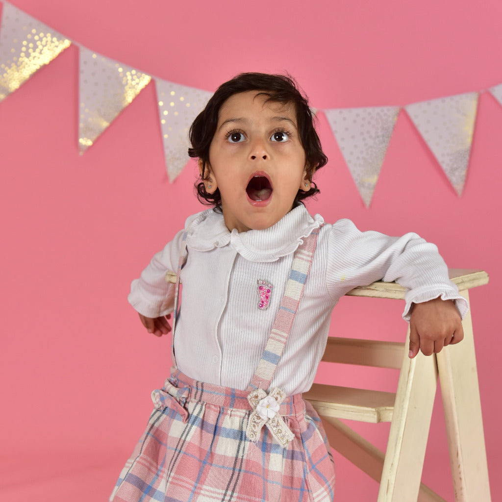 Young girl wearing handcrafted baby feet brooch on pink party outfit—First Step brooch by Little Pink Llama