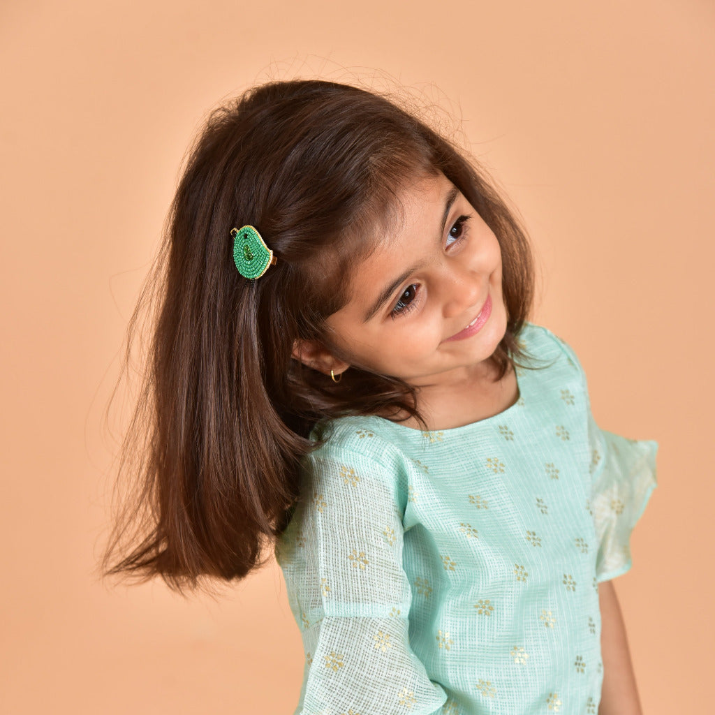 Young girl wearing green handcrafted bird hair clip in light blue floral dress - kids hair accessory