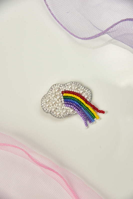 White cloud hair clip with colorful beaded rainbow detail on light fabric - handcrafted kids accessory
