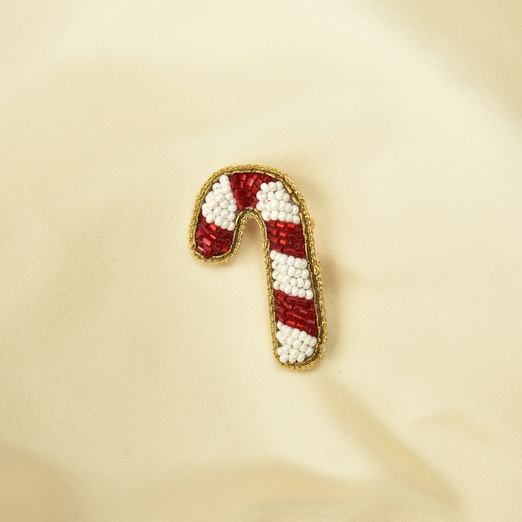 Handmade beaded candy cane hair clip with red and white beads on cream fabric – festive holiday hair pin
