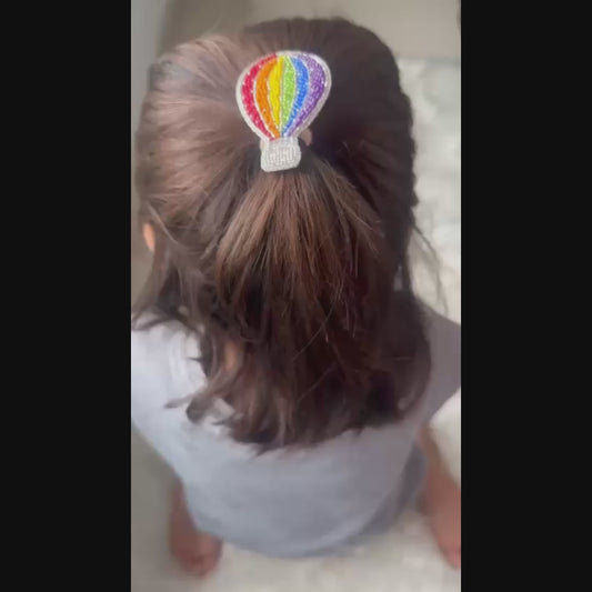 Video showing rainbow hot air balloon hair clip worn in a child's ponytail hairstyle